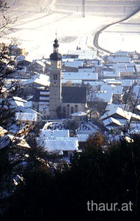 Blick zwischen Bäumen auf das winterliche Thaur