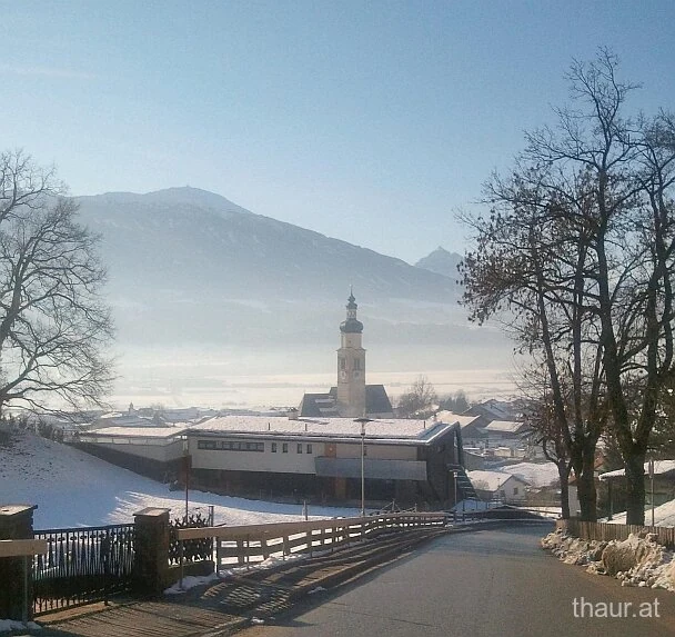 Winterlicher Blick über Thaur mit Kirchturm und Bergen im Hintergrund